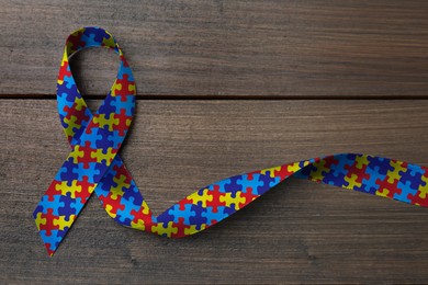 World Autism Awareness Day. Colorful puzzle ribbon on wooden background, top view