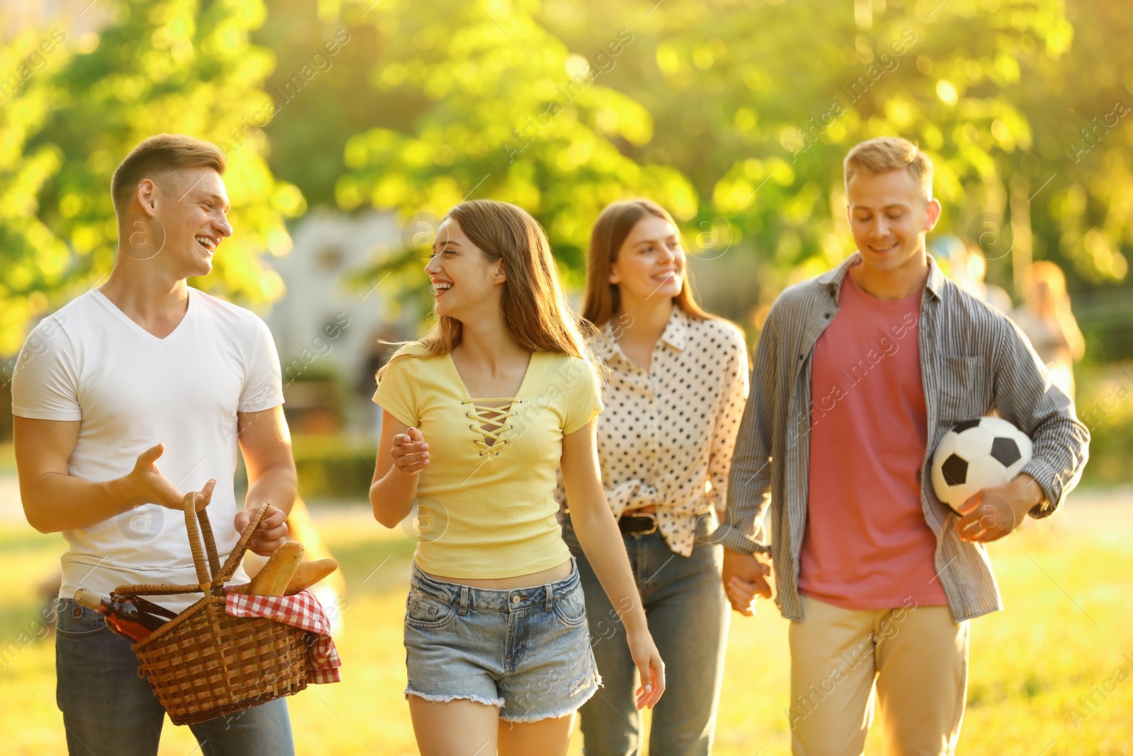 Photo of Young people with picnic basket in park on summer day