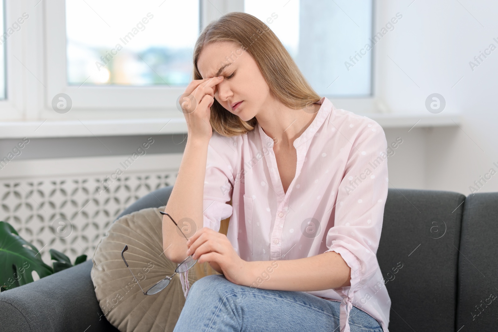 Photo of Overwhelmed young woman with glasses suffering from headache at home