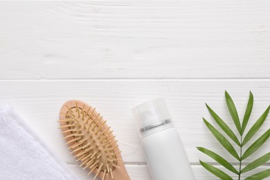 Photo of Dry shampoo spray, hairbrush, towel and green twig on white wooden table, flat lay. Space for text