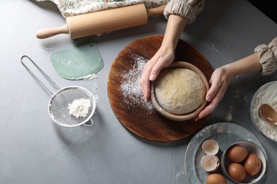 Photo of Woman making dough at grey table, top view