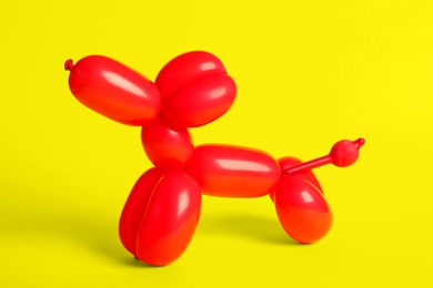 Photo of Red dog figure made of modelling balloon on yellow background