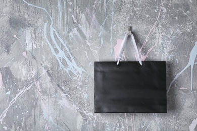 Paper shopping bag with handles hanging on color wall. Mock up for design