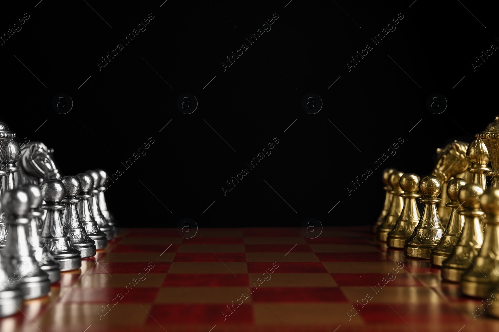 Photo of Many chess pieces on wooden checkerboard against black background, closeup. Space for text