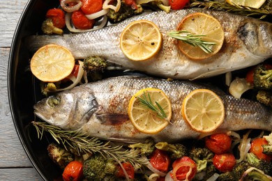 Photo of Baked fish with vegetables, rosemary and lemon on grey wooden table, top view