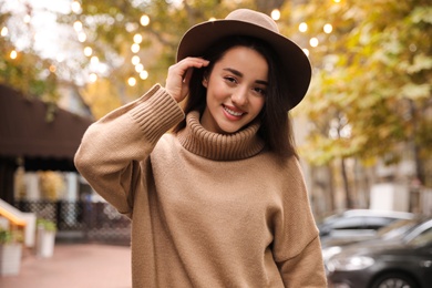 Photo of Young woman wearing stylish clothes on city street. Autumn look