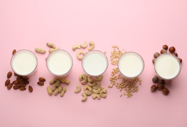 Photo of Different vegan milks and nuts on pink background, flat lay
