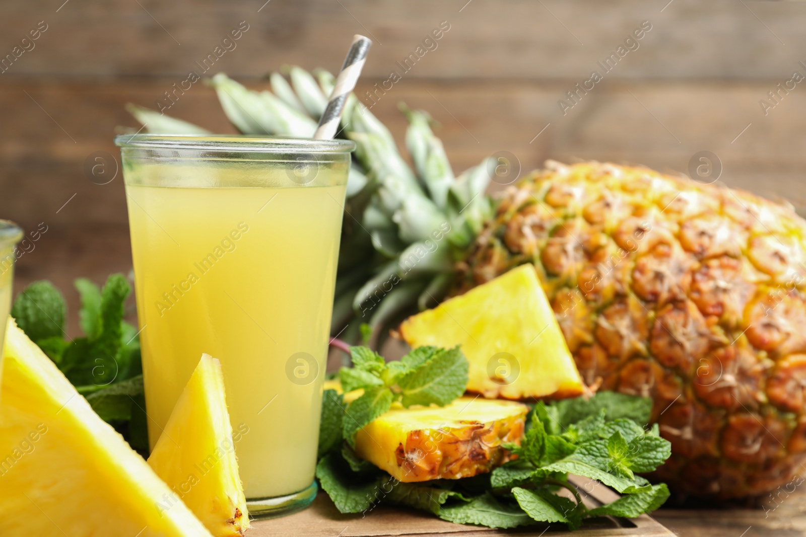 Photo of Delicious pineapple juice and fresh fruit on wooden table, closeup