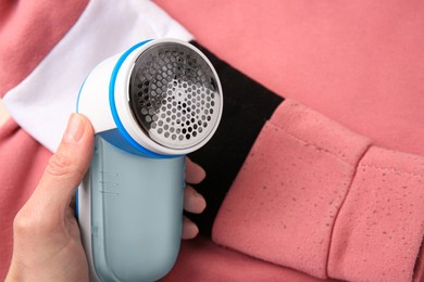 Photo of Woman holding fabric shaver near sweater with lint, closeup