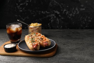 Photo of Delicious hot dogs with bacon, carrot and parsley served on grey table. Space for text