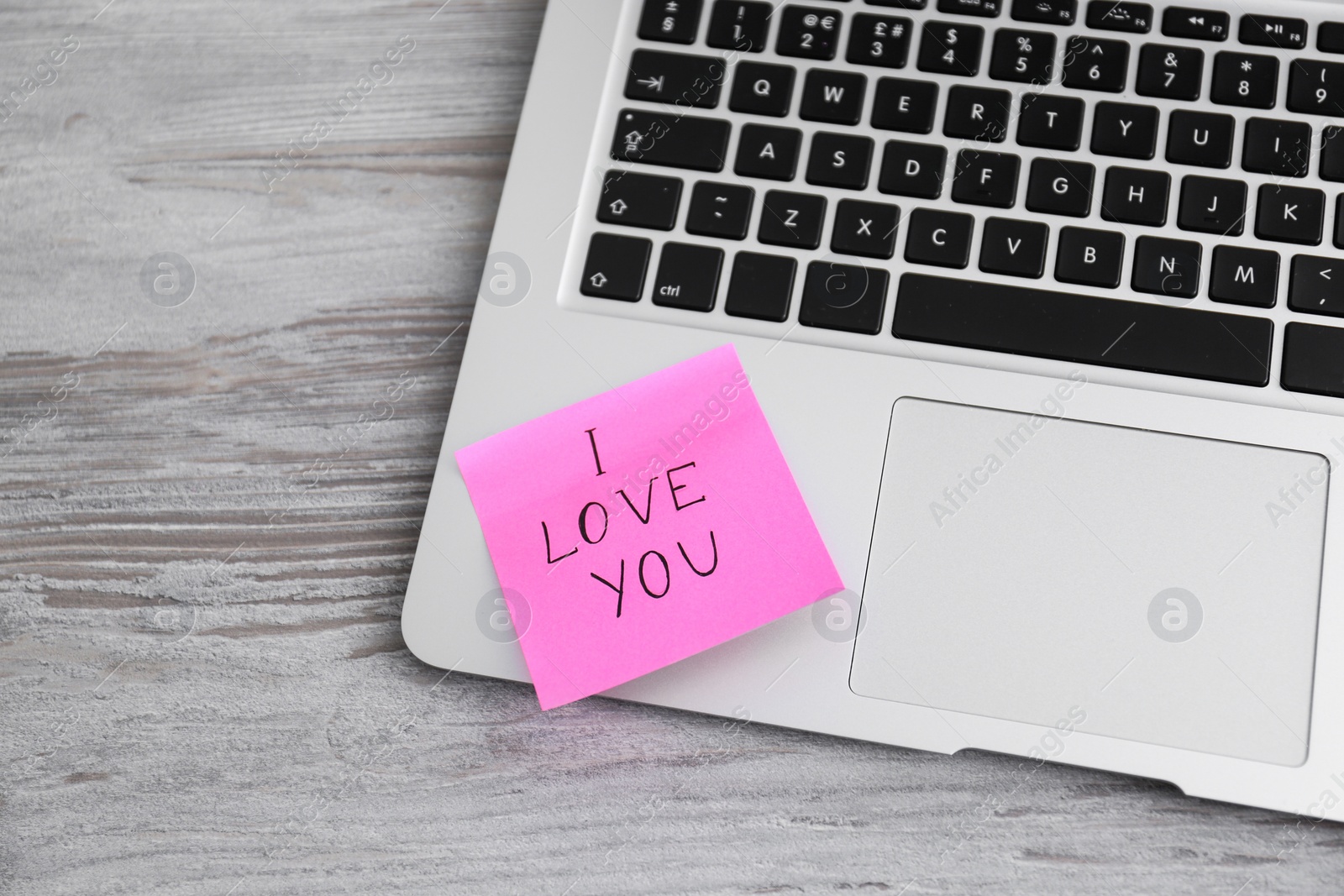 Photo of Memory sticker with phrase I Love You on laptop at table, above view. Valentine's Day celebration