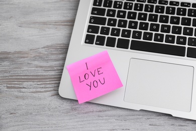 Memory sticker with phrase I Love You on laptop at table, above view. Valentine's Day celebration