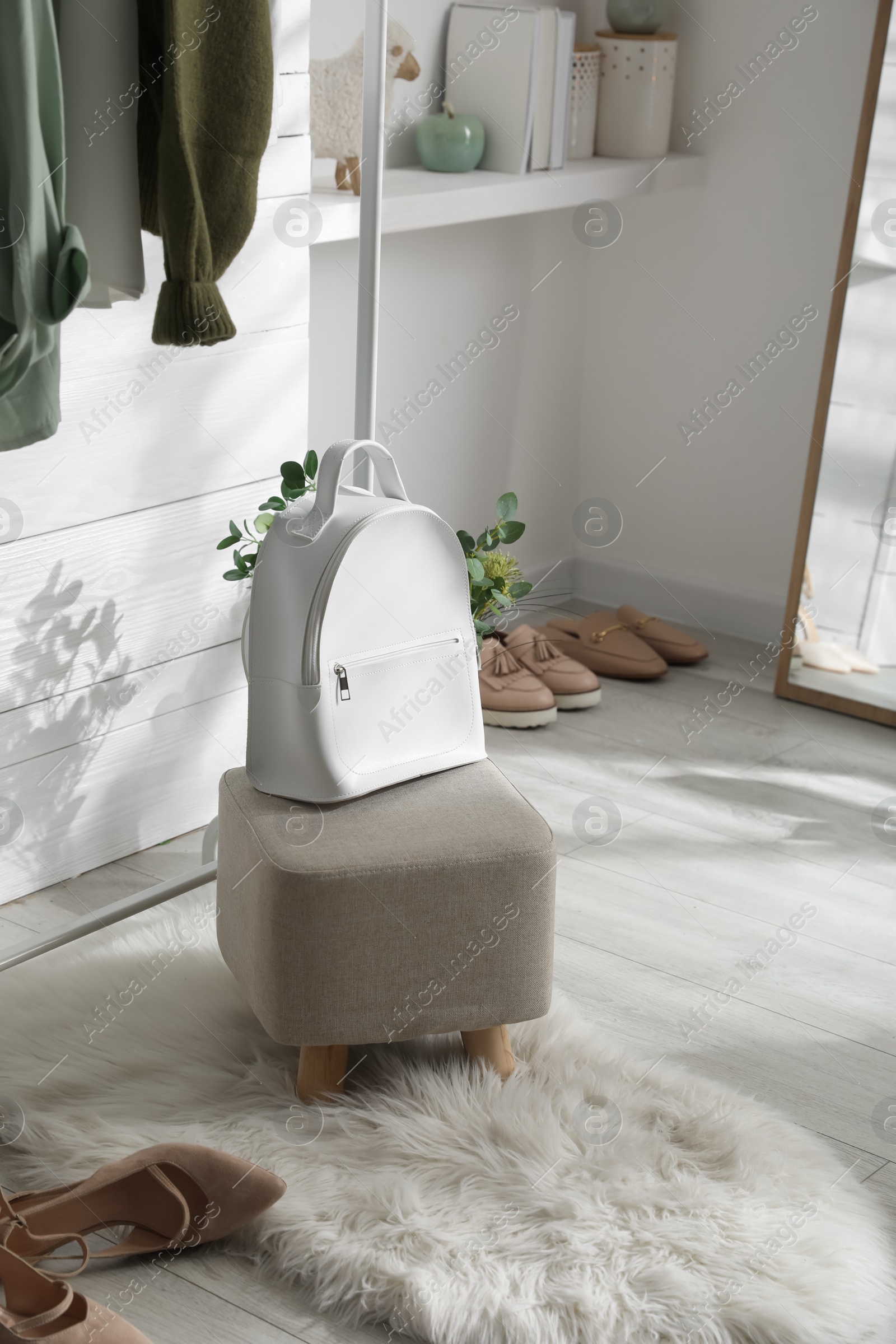 Photo of Stylish backpack on pouf in dressing room