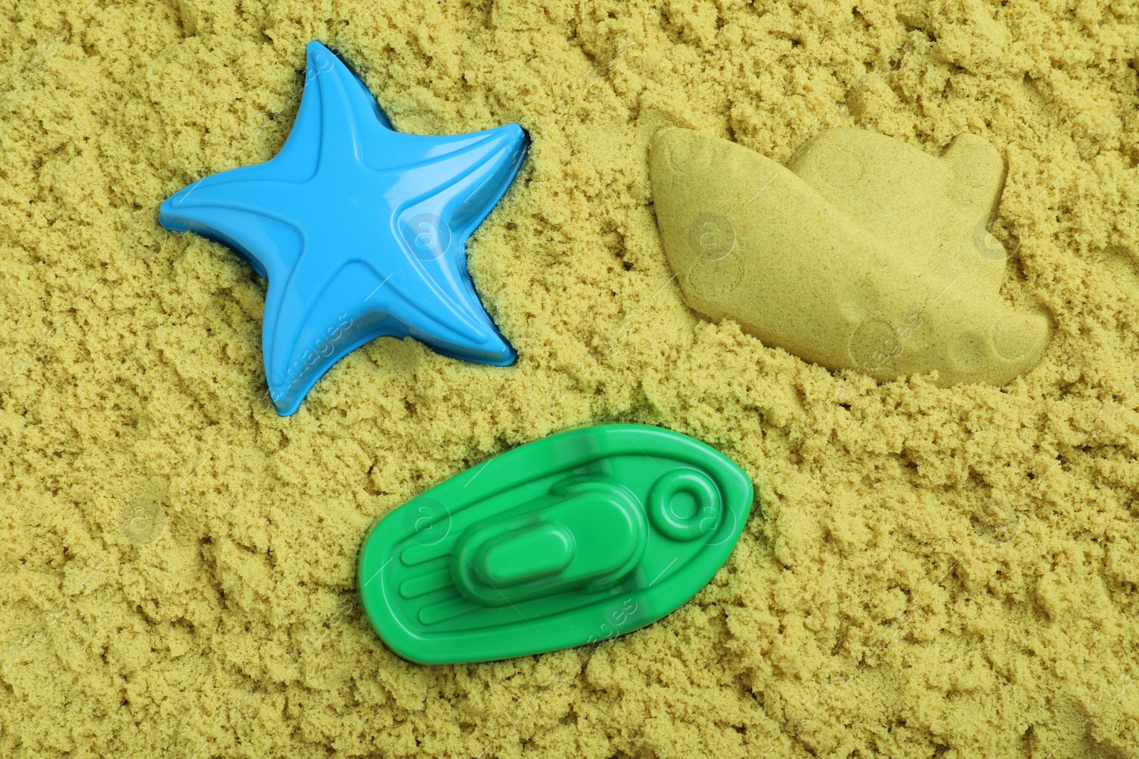 Photo of Toys on yellow kinetic sand, flat lay