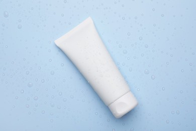 Photo of Wet tube of face cleansing product on light blue background, top view