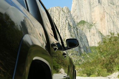 Photo of Picturesque view of big mountains and trees near road with car, closeup