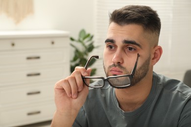 Portrait of sad man with glasses at home. Space for text