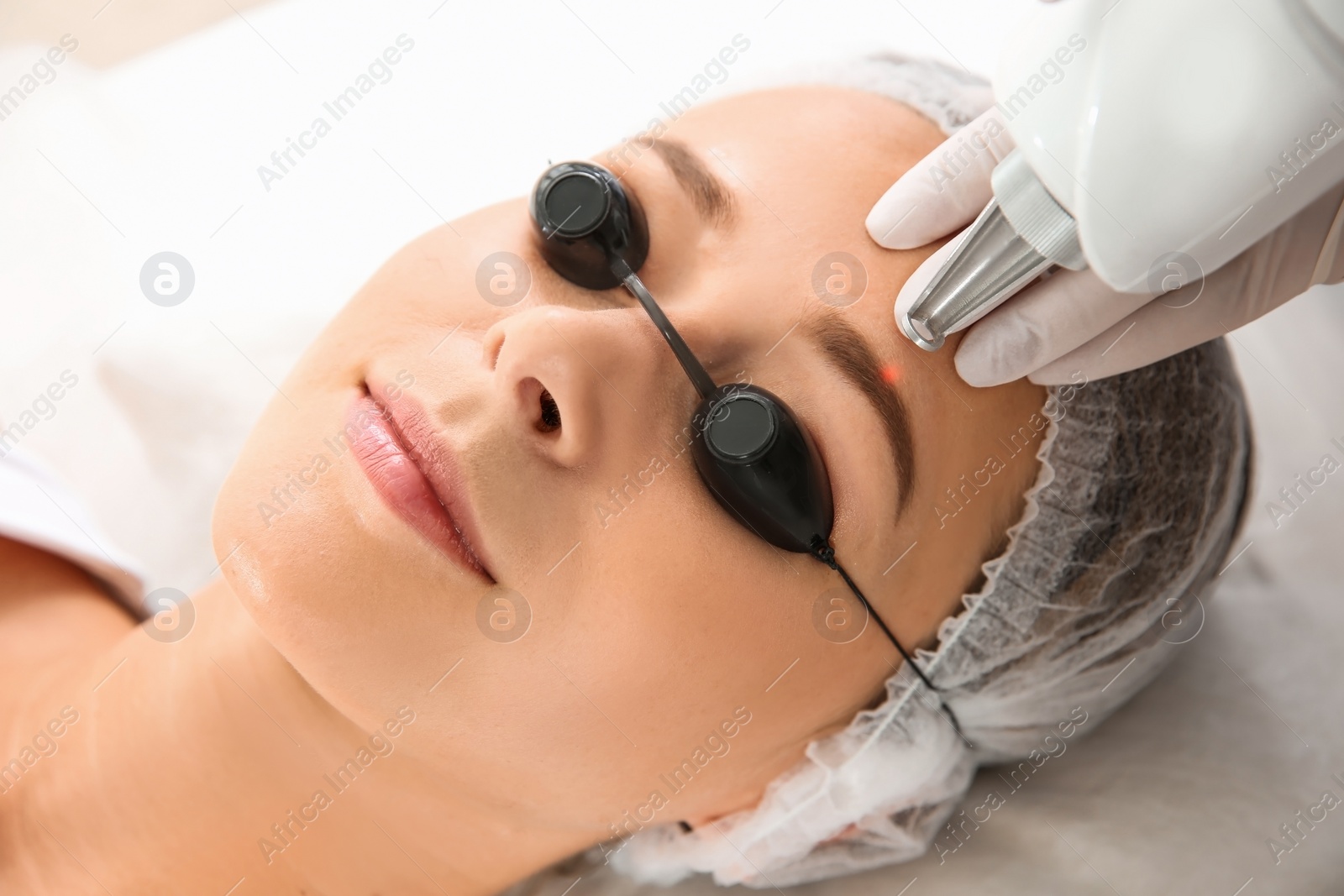 Photo of Young woman undergoing laser removal of permanent makeup in salon. Eyebrow correction