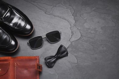 Photo of Stylish bow tie, shoes, wallet and sunglasses on black background, flat lay. Space for text