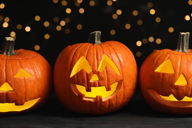 Photo of Pumpkin jack o'lanterns on table against blurred background. Halloween decor