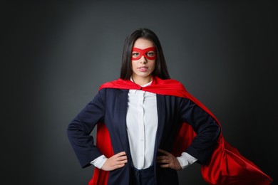 Photo of Confident businesswoman wearing superhero cape and mask on grey background