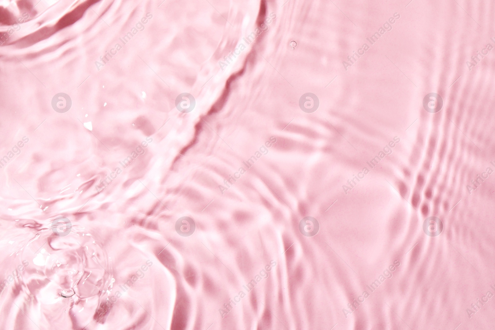 Photo of Closeup view of water with rippled surface on pink background