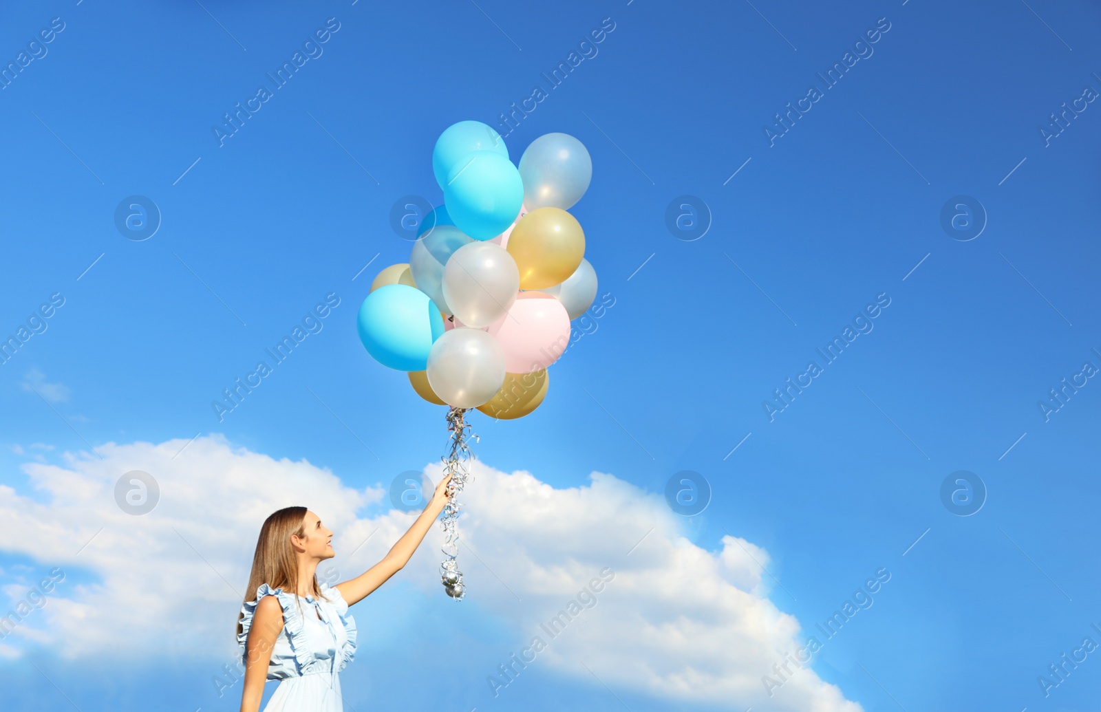 Photo of Beautiful teenage girl holding colorful balloons against blue sky. Space for text