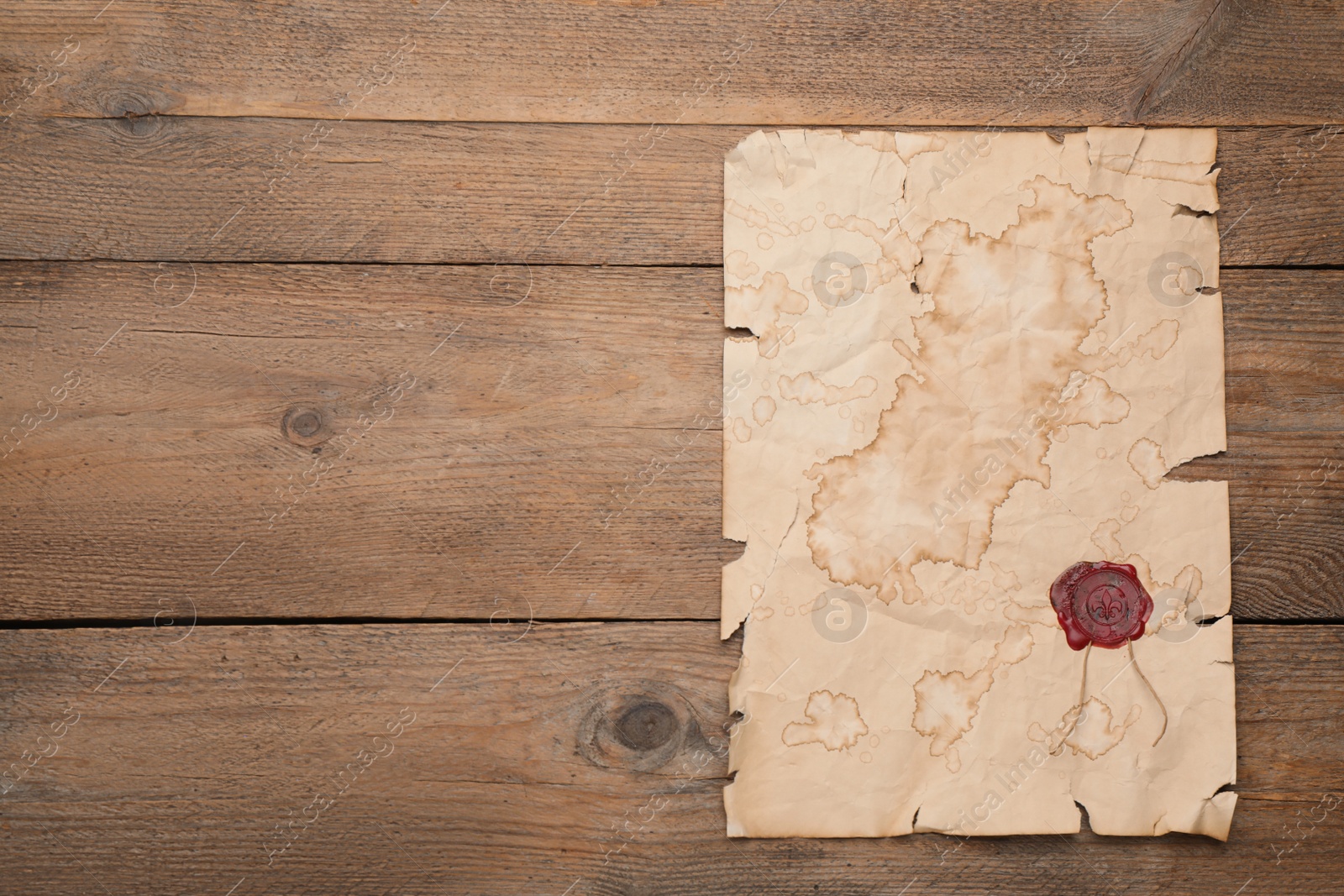 Photo of Sheet of old parchment paper with wax stamp on wooden table, top view. Space for design