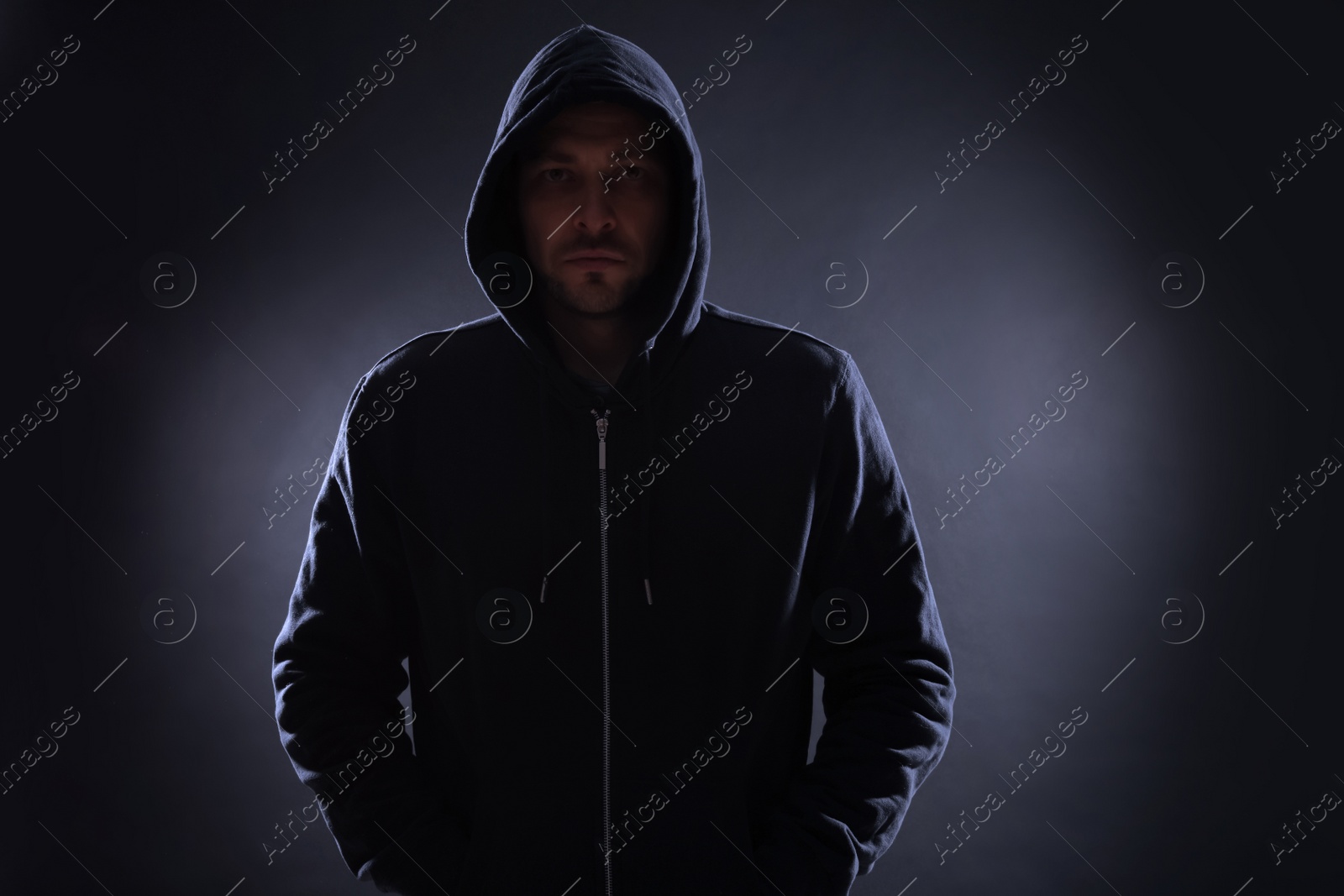 Photo of Mysterious man in hoodie on dark background. Dangerous criminal