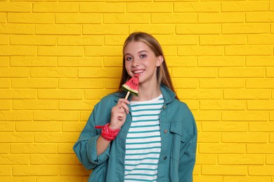 Photo of Beautiful girl with piece of watermelon near yellow brick wall
