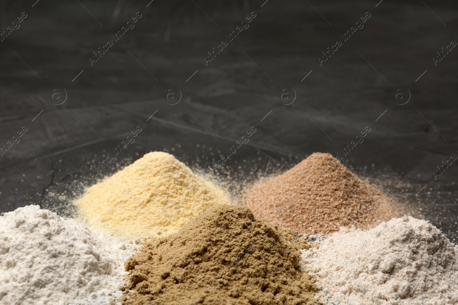 Photo of Piles of different flour types on grey table. Space for text