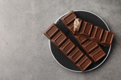 Plate with tasty chocolate bars on grey table, top view. Space for text