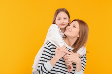 Portrait of happy mother and her cute daughter on orange background. Space for text