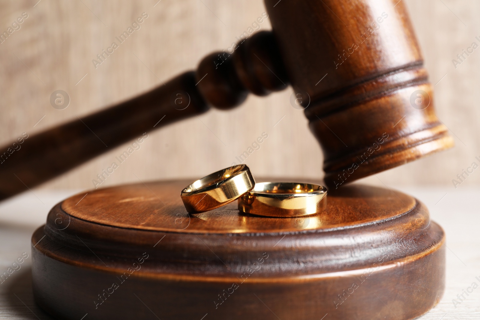 Photo of Divorce concept. Wooden gavel and wedding rings on white table, closeup
