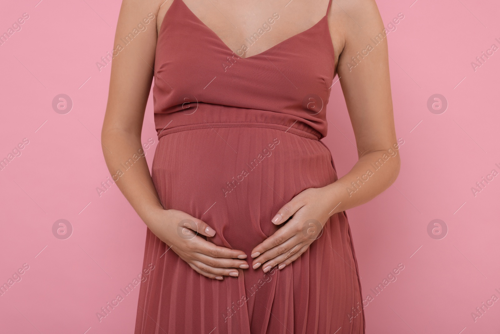 Photo of Pregnant woman in dress on pink background, closeup