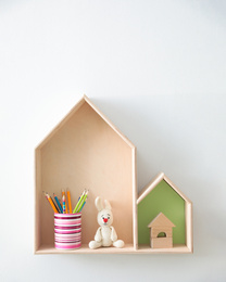 Photo of Different house shaped shelves with toys on white wall. Interior design