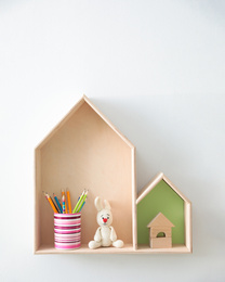 Different house shaped shelves with toys on white wall. Interior design