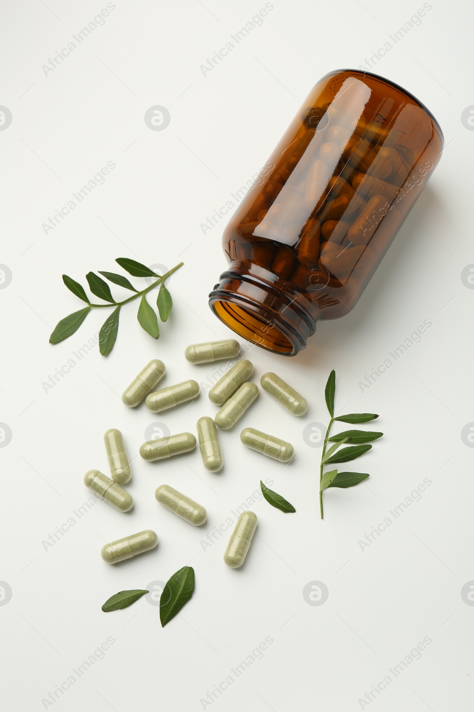 Photo of Bottle, vitamin capsules and leaves on white background, flat lay