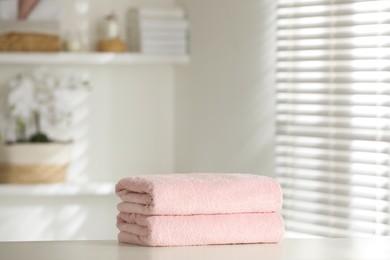 Photo of Stack of clean soft towels on white table indoors