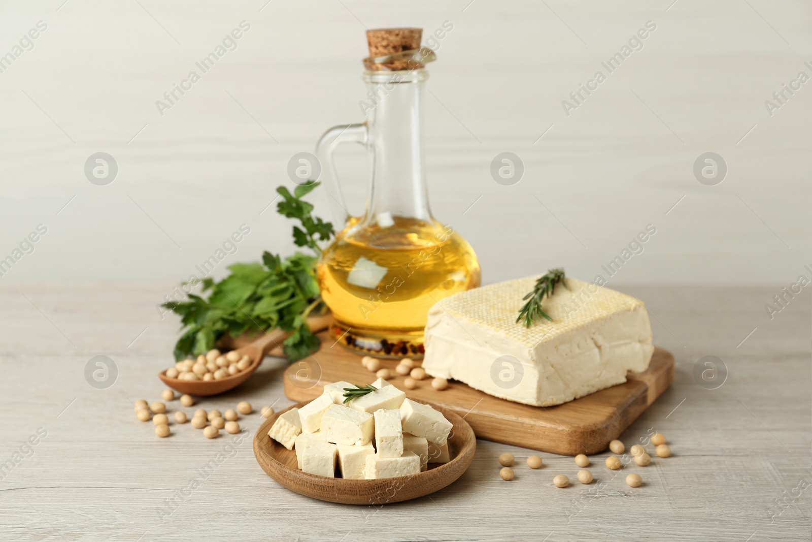 Photo of Pieces of delicious tofu with herbs, oil and soy on white table