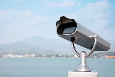 Metal tower viewer installed near sea, space for text. Mounted binoculars