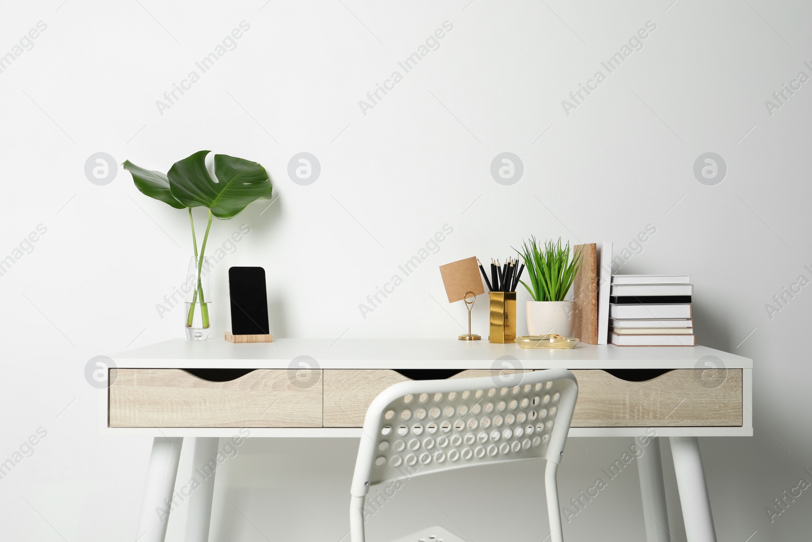 Photo of Comfortable workplace with white desk near wall