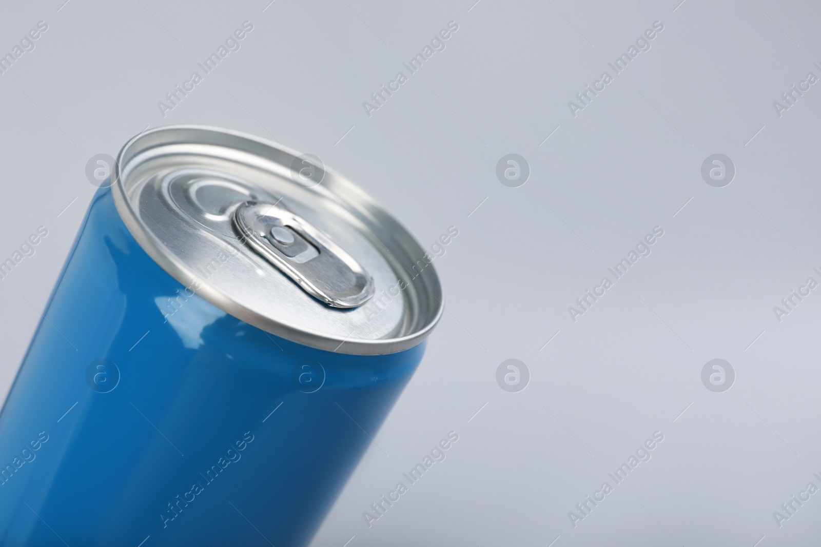 Photo of Blue can of energy drink on light grey background, closeup. Space for text