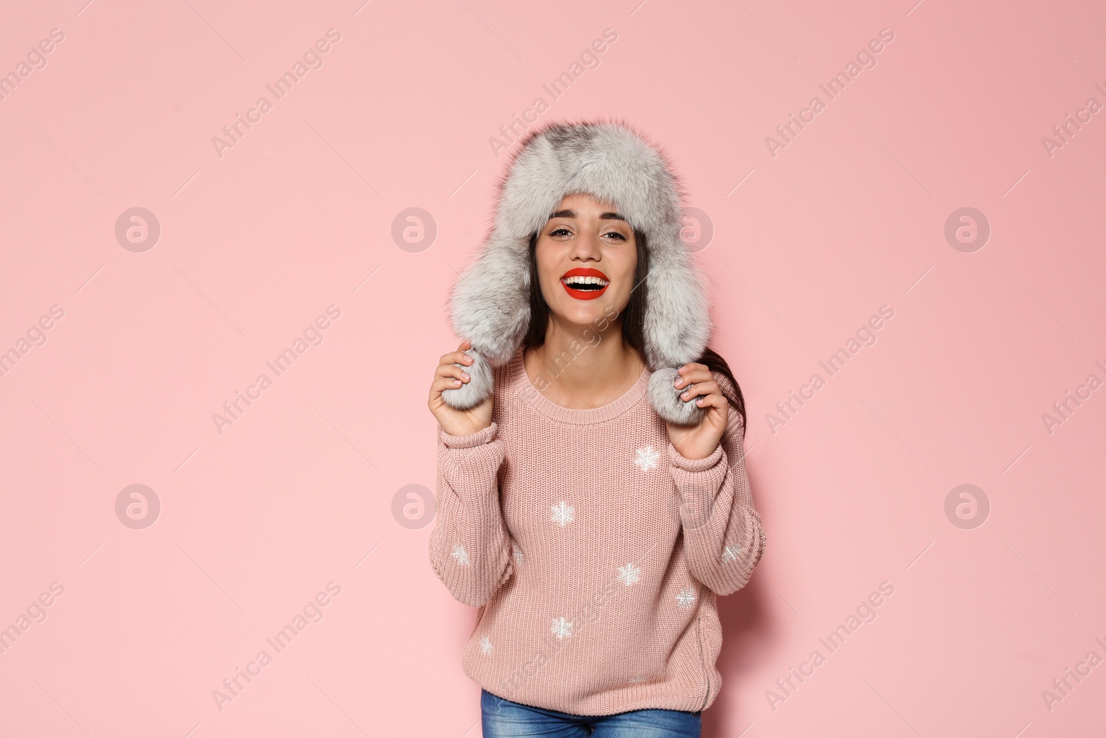 Photo of Young woman in warm sweater and hat on color background. Celebrating Christmas