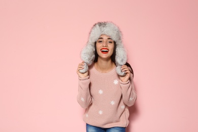 Photo of Young woman in warm sweater and hat on color background. Celebrating Christmas