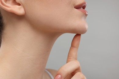 Photo of Woman touching her chin on grey background, closeup