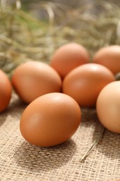 Photo of Fresh chicken eggs on burlap fabric, closeup