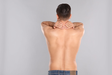 Man suffering from pain in neck on light grey background. Visiting orthopedist