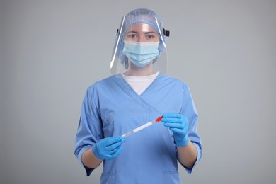 Laboratory testing. Doctor with cotton swab and tube on light grey background