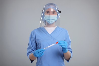 Photo of Laboratory testing. Doctor with cotton swab and tube on light grey background